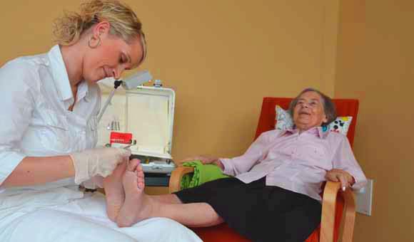 Eine ältere Dame bekommt eine Fußpflege